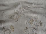 a close up of a piece of embroidered fabric with flowers and birds on it