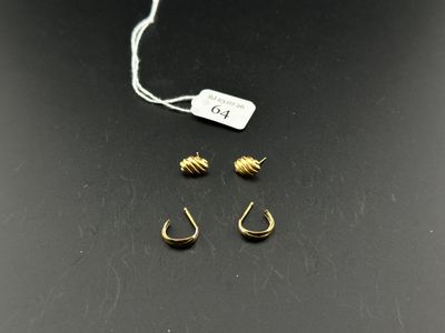 three pairs of gold earrings and a tag on a black surface