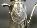 a silver tea pot with a metal handle on a table