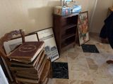 a room with a chair, books, and pictures on the floor