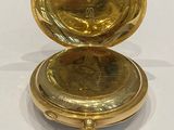 a gold pocket watch sitting on top of a white table
