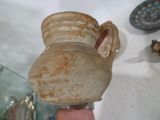 une main tenant un grand vase orné d'un visage