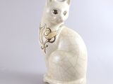 un chat blanc avec un collier doré, assis sur une surface blanche