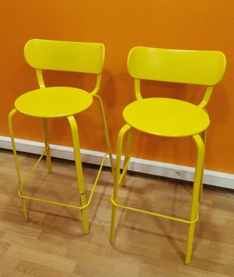 pair of yellow metal stools against an orange wall in a room