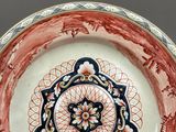 a red and white plate with a floral design on it