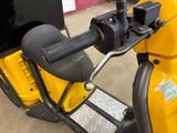 a close up of a yellow scooter parked in a parking lot