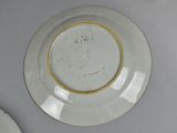 a white plate with a gold rim on a table