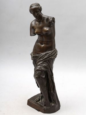 une statue en bronze représentant une femme debout sur un socle en marbre