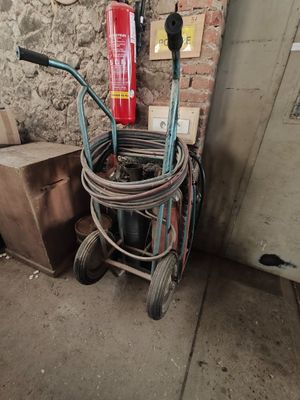 un chariot équipé d'un tuyau et d'un extincteur, à côté d'un mur de briques