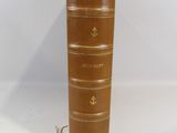 un vieux livre marron sur lequel est posée une bougie jaune