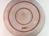 a pink plate with a brown rim sitting on a white table
