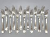 six forks are arranged in a row on a gray surface