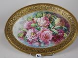 a gold plate with a painting of roses on it