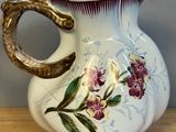a white vase with purple flowers on it sitting on a table