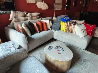 un salon avec un canapé, un fauteuil, un pouf et une table basse