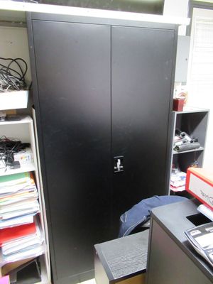 une armoire noire dans un coin d'une pièce où il y a beaucoup de livres