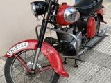 a red motorcycle parked on the sidewalk next to a building