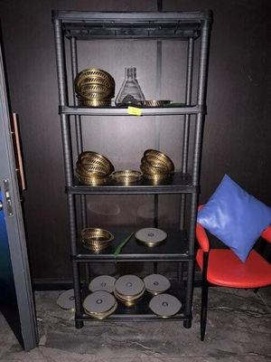 une étagère noire sur laquelle sont posées des pièces d'or et une chaise rouge
