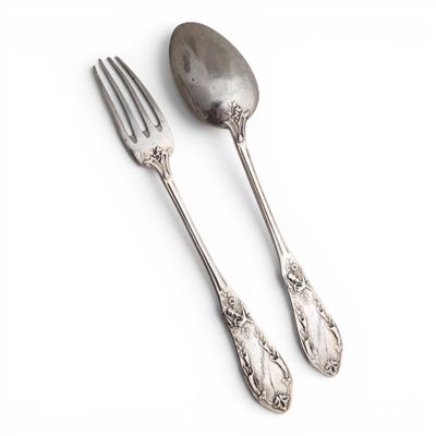 two silver spoons and a fork on a white surface