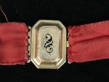 a small silver watch with a red band on a black surface