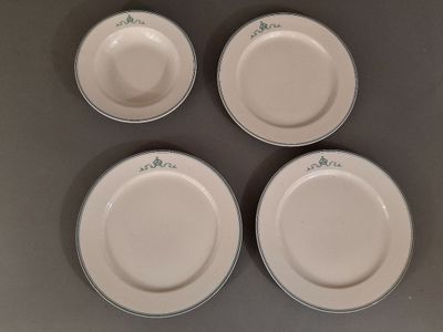 quatre assiettes blanches ornées de motifs verts sont disposées sur une surface grise