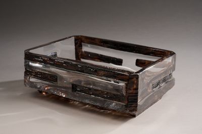 une boîte en verre munie d'une poignée, posée sur une surface blanche