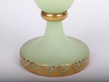 a green glass vase with a gold rim on a white background