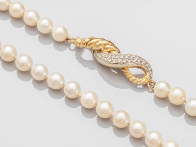 un gros plan sur un collier de perles muni d'un fermoir en or
