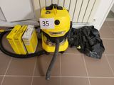 un aspirateur jaune posé par terre à côté d'un sac noir