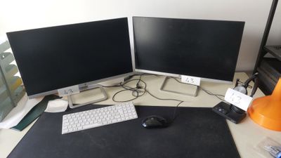 deux écrans d'ordinateur posés sur un bureau, avec une souris et un clavier
