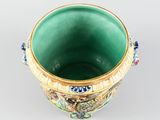 a green and gold vase sitting on a white surface