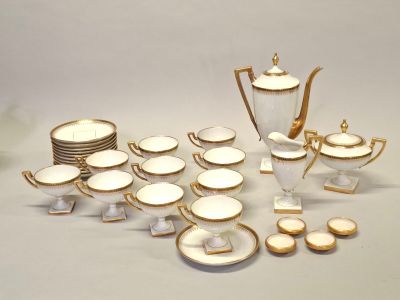 beaucoup d'assiettes et de tasses dorées et blanches sur la table
