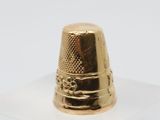 a gold thimble sitting on top of a clear box