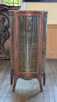 une petite armoire avec une porte vitrée, au milieu d'une pièce