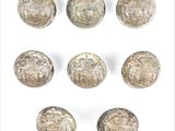 six boutons argentés ornés de motifs sur un fond blanc