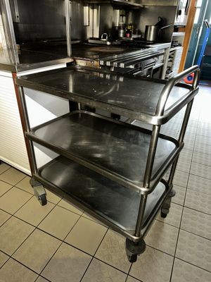 a kitchen with a stove, oven, and a cart in it