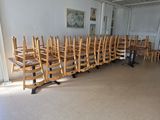 Des tables et des chaises sont alignées dans une pièce aux murs blancs.