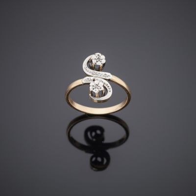 a gold ring with two diamonds on a black surface