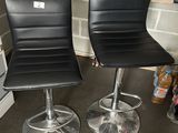 two black leather bar stools sitting on a counter