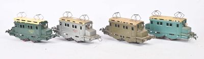 quatre petits trains miniatures posés les uns à côté des autres sur une surface blanche