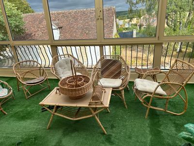 une photo d'une terrasse avec des chaises en osier et une table