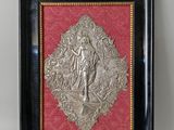une plaque ancienne en métal argenté représentant une femme sur fond rouge