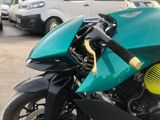 a green motorcycle parked in a parking lot next to a white van
