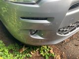 a close up of a car ' s front bumper with grass growing on the ground