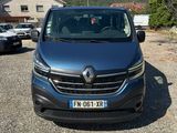 the front of a blue van parked in a parking lot with mountains in the background