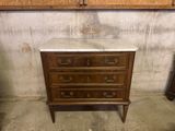 a marble top chest of drawers in the corner of a room