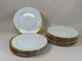 several white plates with gold rims stacked on top of each other