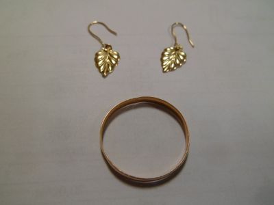 une bague en or et deux boucles d'oreilles en feuille d'or posées sur une table