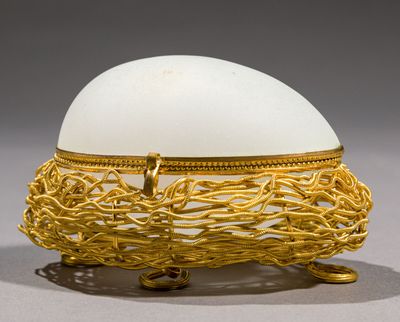 un œuf blanc posé sur un panier en fil d'or