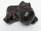 a small statue of a cat laying down on a white surface